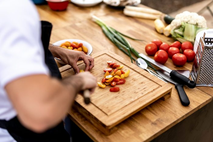 a person cutting up vegetables on a cutting board