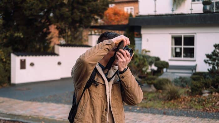 man in brown coat holding black camera