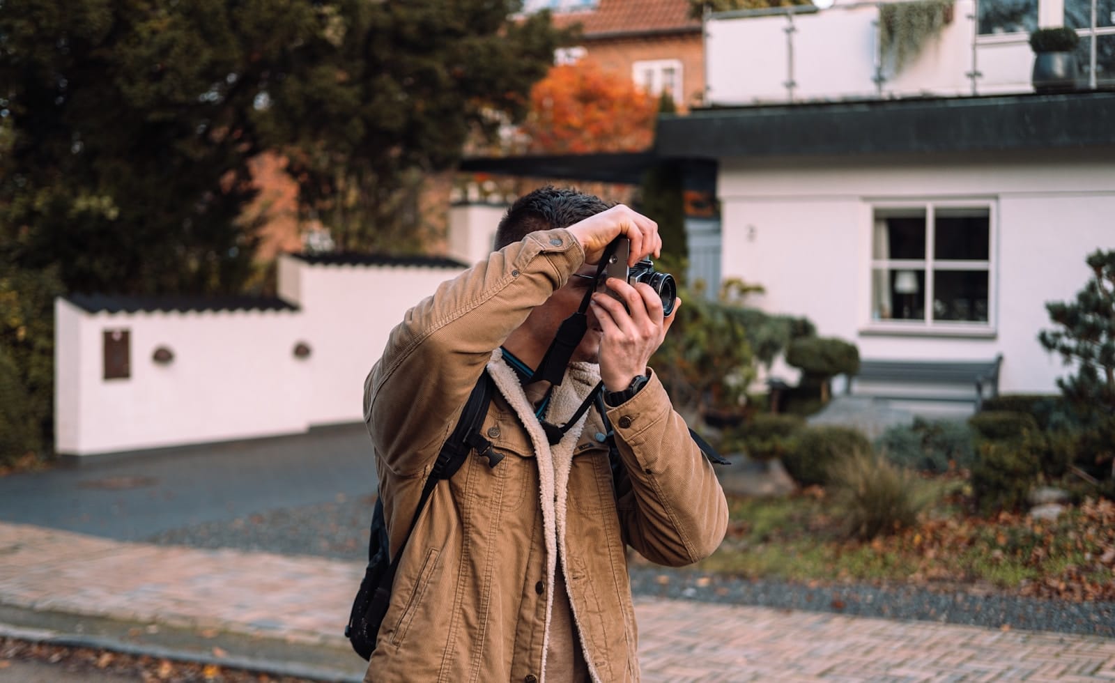 man in brown coat holding black camera