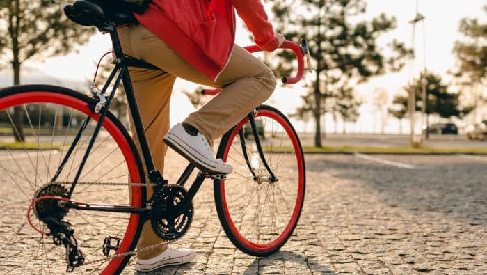 close up legs sneakers hands steering wheel hipster style bearded man red hoodie beige trousers riding alone with backpack bicycle healthy active lifestyle traveler backpacker 1