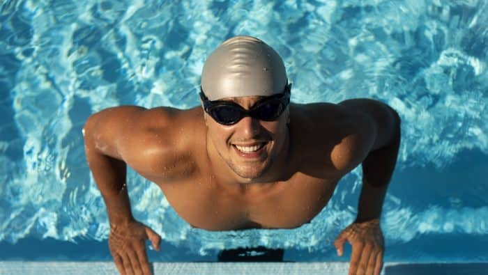 smiley male swimmer posing with goggles cap pool 1